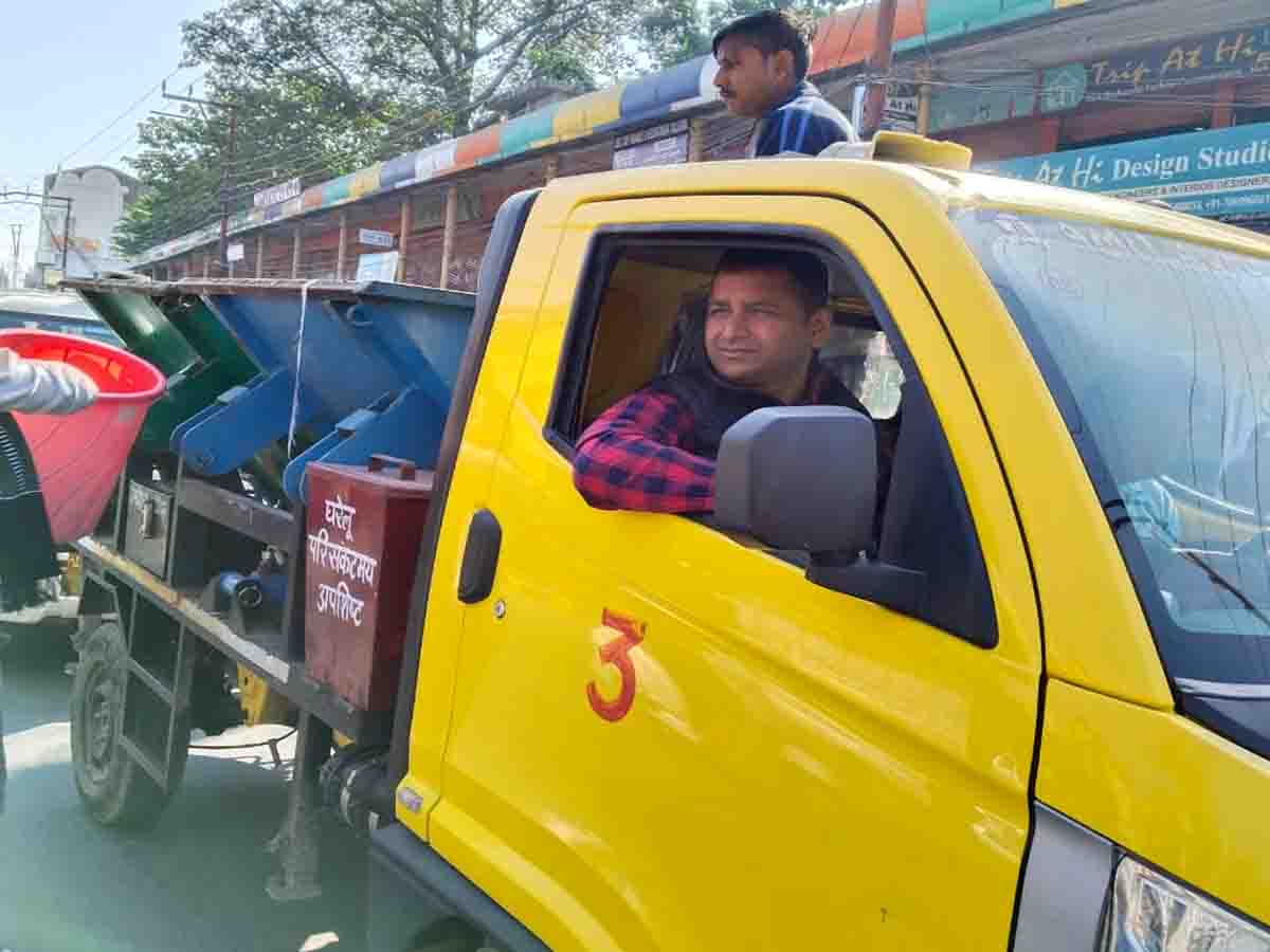 Municipal commissioner drives garbage collection vehicle as workers go